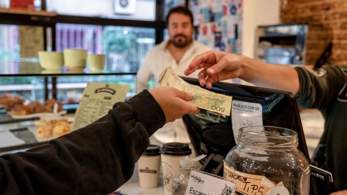A customer pays with Argentine peso banknotes at a cafe in Buenos Aires on April 14.