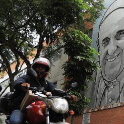 Un motociclista circula frente a un mural que representa al difunto Papa Francisco en el Hogar Infantil San José de Medellín, Antioquia, Colombia. | Foto:JAIME SALDARRIAGA / AFP