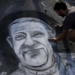 El artista argentino Javier Sativa dibuja el rostro del difunto Papa Francisco en una calle frente a la entrada de la Catedral de Buenos Aires. | Foto:LUIS ROBAYO / AFP