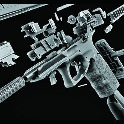 Despiece interno de una pistola, donde se aprecian el armazón, el cañón y la cola del disparador con su resorte y mecanismo, entre  otros componentes.