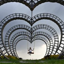 Una niña se columpia en un columpio con forma de corazón en un parque a las afueras de Kiev, la capital ucraniana, durante un cálido día de primavera, durante la invasión rusa a Ucrania. | Foto:SERGEI SUPINSKY / AFP