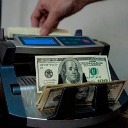 A worker uses a counting machine for US$100 US banknotes at a currency exchange house in Buenos Aires.