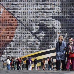 La gente pasa junto a una pancarta gigante de "Izando la Bandera sobre el Reichstag", que representa a un soldado del Ejército Rojo izando la Bandera Roja de la URSS en lo alto del edificio del Reichstag en Berlín. Esta pancarta está hecha con 4500 retratos de veteranos de la Segunda Guerra Mundial y lleva el mensaje "Nadie es olvidado, nada es olvidado". | Foto:OLGA MALTSEVA / AFP