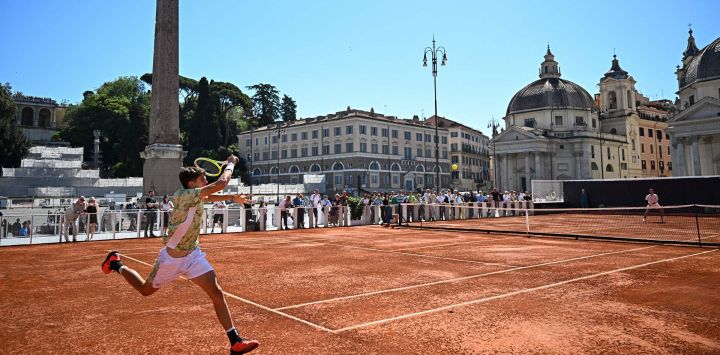 El italiano Lorenzo Sciahbasi devuelve la pelota al italiano Alberto Bronzetti en una cancha de tenis instalada en la Piazza del Popolo de Roma.