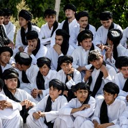 Escolares afganos con los nuevos uniformes impuestos por los talibanes, compuestos por turbantes y túnicas largas, se reúnen para un evento en una escuela de Herat. | Foto:Mohsen Karimi / AFP