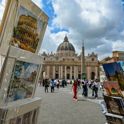 Esta fotografía muestra productos turísticos, incluidas postales, en puestos, con la Basílica de San Pedro del Vaticano al fondo, en Roma. | Foto:GABRIEL BOUYS / AFP