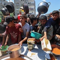 Palestinos hacen fila para recibir una ración de comida caliente distribuida por un comedor social en el campo de refugiados de Nuseirat, en el centro de la Franja de Gaza. La crisis humanitaria en la asediada Franja de Gaza se ha agravado significativamente desde que Israel bloqueó la entrada de toda ayuda humanitaria al territorio el 2 de marzo, días antes de reanudar su campaña militar tras el fracaso del alto el fuego. | Foto:Eyad Baba / AFP