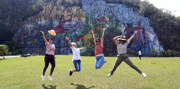 Imagen de jóvenes turistas saltando frente al Mural de la Prehistoria, una obra de 80 metros de altura por 120 de ancho hecha sobre las rocas para representar el pasado geológico y biológico de la región, en el valle de Viñales, en la provincia de Pinar del Río, Cuba.