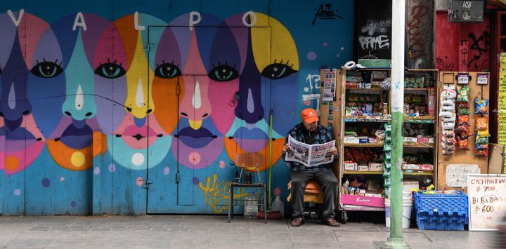 Un vendedor ambulante espera por clientes mientras lee un periódico en una calle, en la ciudad de Valparaíso, Chile.