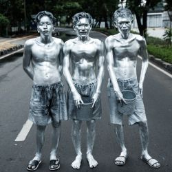 Esta foto muestra a los artistas callejeros Keris Munandar (der.), su hermano Ari Munandar (centro) y su vecino Riyan Ahmad Fazriyansah posando tras su actuación en una intersección de Yakarta, Indonesia. | Foto:Yasuyoshi Chiba / AFP