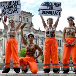 Miembros del grupo activista feminista FEMEN, en topless y con inscripciones en el pecho que dicen "Nunca más es ahora", "Fascismo basura", "Nunca más nazis", "Mantén tu espíritu limpio", "Recuerda el pasado" y "Abajo la suciedad marrón", posan cerca del Reichstag (al fondo), sede del Bundestag (cámara baja del parlamento), mientras organizan una "Limpieza de primavera para la democracia" para manifestarse contra el fascismo y a favor de la democracia en Berlín. | Foto:RALF HIRSCHBERGER / AFP