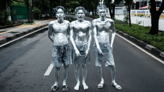 Fotogaleria Esta foto muestra a los artistas callejeros Keris Munandar (der.), su hermano Ari Munandar (centro) y su vecino Riyan Ahmad Fazriyansah posando tras su actuación en una intersección de Yakarta, Indonesia