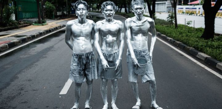Esta foto muestra a los artistas callejeros Keris Munandar (der.), su hermano Ari Munandar (centro) y su vecino Riyan Ahmad Fazriyansah posando tras su actuación en una intersección de Yakarta, Indonesia.