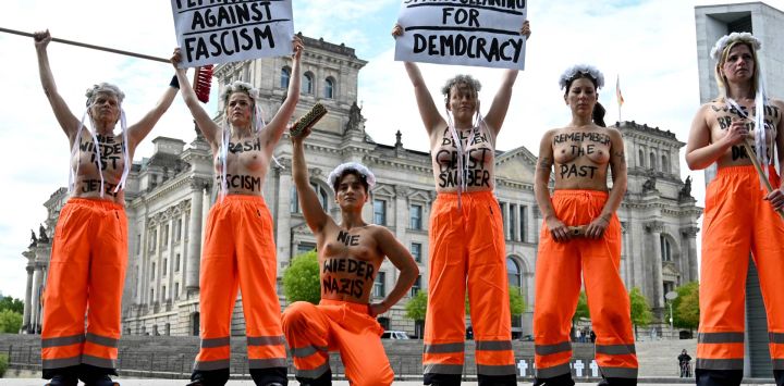 Miembros del grupo activista feminista FEMEN, en topless y con inscripciones en el pecho que dicen "Nunca más es ahora", "Fascismo basura", "Nunca más nazis", "Mantén tu espíritu limpio", "Recuerda el pasado" y "Abajo la suciedad marrón", posan cerca del Reichstag (al fondo), sede del Bundestag (cámara baja del parlamento), mientras organizan una "Limpieza de primavera para la democracia" para manifestarse contra el fascismo y a favor de la democracia en Berlín.