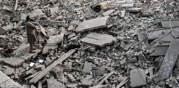 Residentes locales permanecen sobre los escombros de las estructuras destruidas en el complejo gubernamental de salud y educación en Muridke, a unos 30 kilómetros de Lahore, tras los ataques indios.