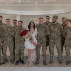 Anna, novia, y su novio, Pavlo Chornobai, militar ucraniano de la Brigada Azov, posan para una foto con los compañeros soldados de Pavlo durante su ceremonia de boda en el registro civil de Sloviansk, región oriental de Donetsk, en medio de la invasión rusa de Ucrania. La guerra infundió urgencia al compromiso de las parejas de militares ucranianos, quienes no ven sentido en esperar una paz que parece un mero espejismo. | Foto:ROMAN PILIPEY / AFP