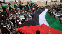 Palestinos ondean banderas nacionales mientras participan en una concentración para conmemorar el 77 aniversario de la "Nakba" en la ciudad de Ramala