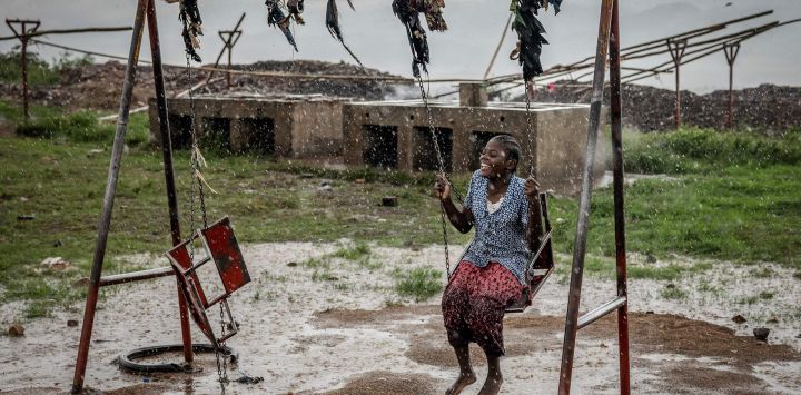 Un joven refugiado congoleño juega en un columpio bajo una intensa lluvia mientras esperan su reubicación en el Centro de Tránsito de Cishemere, cerca de Buganda.