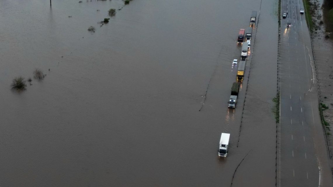 In this aerial view, vehicles drive along a flooded road following heavy rainstorms in Campana, Buenos Aires Province on May 17, 2025. 