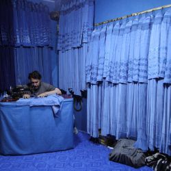 Un sastre afgano cose burkas en una tienda de Herat. | Foto:Mohsen Karimi / AFP