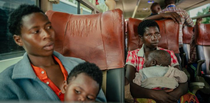 Dos personas desplazadas, presuntamente de nacionalidad ruandesa, se encuentran sentadas en un gran autobús con sus hijos tras ser inspeccionadas en la frontera entre la República Democrática del Congo y Ruanda, en Goma.