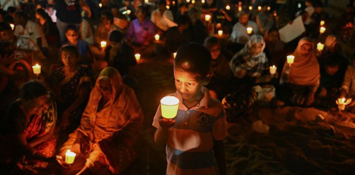 Personas con velas asisten a una ceremonia conmemorativa en honor a las víctimas de la Masacre de Mullivaikkal, en conmemoración del 16.º aniversario del Día del Recuerdo del Genocidio Tamil, en la playa Edward Elliot de Chennai.