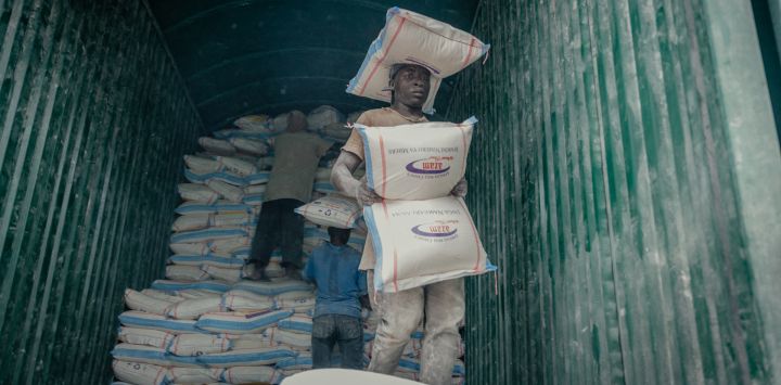 Un joven porteador transporta mercancías para sus clientes mientras descarga un contenedor de harina en el mercado de Birere, Goma.