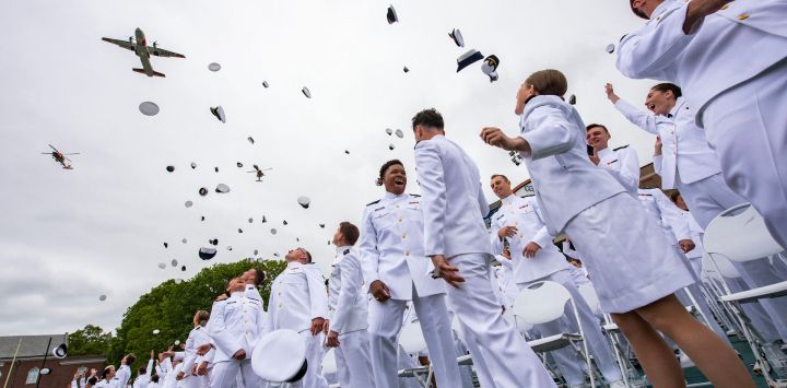 Oficiales recién comisionados lanzan sus sombreros durante la 144.ª ceremonia de graduación de la Academia de la Guardia Costera de EE. UU. en New London, Connecticut.