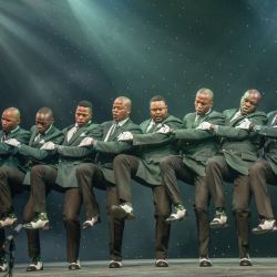Un grupo tradicional Isicathamiya baila mientras interpreta una canción en el escenario durante la edición 2025 del Concierto Isicathamiya en el Teatro Natal Playhouse de Durban. | Foto:RAJESH JANTILAL / AFP