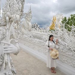 Esta fotografía muestra a una turista posando en el templo budista Wat Rong Khun, conocido popularmente como el "Templo Blanco", en la provincia de Chiang Rai, al norte de Tailandia. | Foto:MANAN VATSYAYANA / AFP