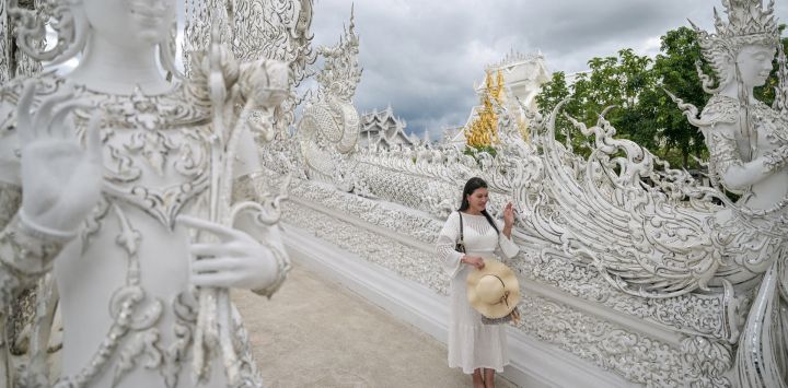 Esta fotografía muestra a una turista posando en el templo budista Wat Rong Khun, conocido popularmente como el "Templo Blanco", en la provincia de Chiang Rai, al norte de Tailandia.