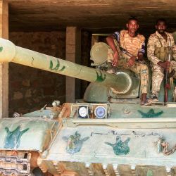 Soldados del ejército sudanés sentados sobre un tanque estacionado tras capturar una base utilizada por las Fuerzas de Apoyo Rápido (FAR), tras la evacuación de este grupo de la zona de Salha en Omdurmán, ciudad hermanada con la capital de Sudán. Sudán, el tercer país más grande de África, ha sido devastado por más de dos años de guerra entre el ejército y las FAR. El conflicto ha causado la muerte de decenas de miles de personas, el desplazamiento de 13 millones y ha generado lo que Naciones Unidas describe como la peor crisis humanitaria del mundo. | Foto:Ebrahim Hamid / AFP