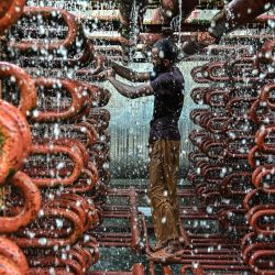 Un trabajador limpia las líneas de una torre de enfriamiento en una fábrica de hielo en un caluroso día de verano en Karachi, Pakistán. | Foto:Asif Hassan / AFP