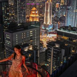Una mujer posa para una foto con el horizonte nocturno de fondo en Kuala Lumpur, Malasia. | Foto:JAM STA ROSA / AFP