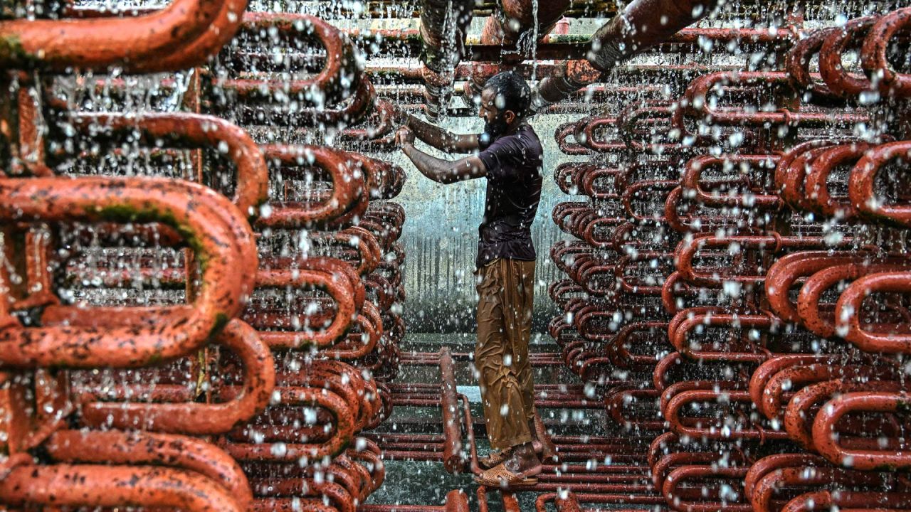 Un trabajador limpia las líneas de una torre de enfriamiento en una fábrica de hielo en un caluroso día de verano en Karachi, Pakistán. | Foto:Asif Hassan / AFP