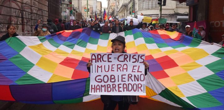 Personas sostienen una bandera wiphala y pancartas durante una marcha en contra del presidente boliviano, Luis Arce, en La Paz, Bolivia.