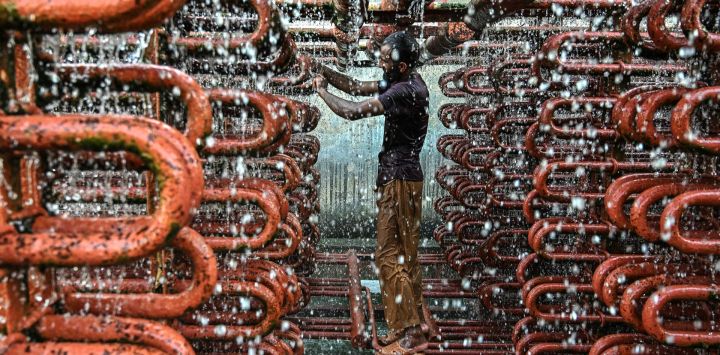 Un trabajador limpia las líneas de una torre de enfriamiento en una fábrica de hielo en un caluroso día de verano en Karachi, Pakistán.