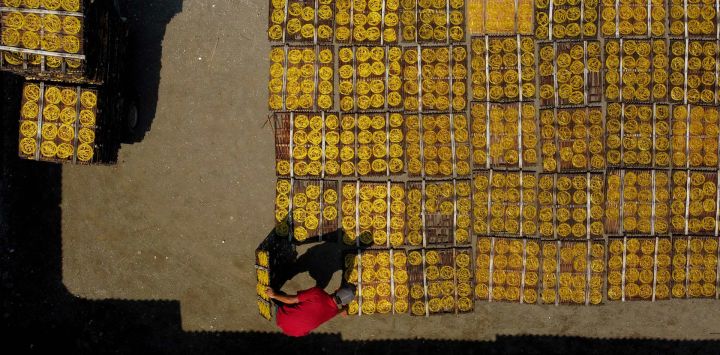 Vista aérea tomada con un dron de un trabajador colocando galletas amarillas tradicionales en platos de bambú previo a secarlas en un taller casero, en la aldea de Karadenan, en la regencia de Bogor, Java Occidental, Indonesia.