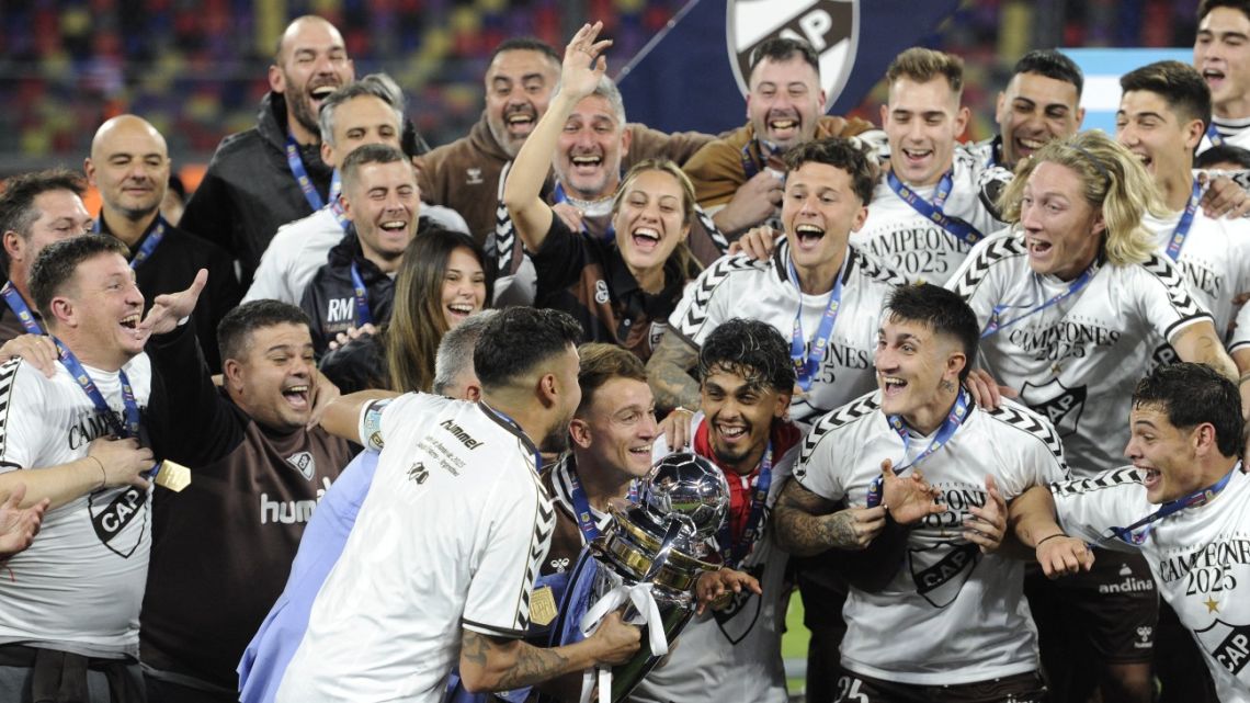 Platense players celebrate with the trophy after winning the Argentine Professional Football League 2025 Apertura Tournament final match against Huracán at the Madre de Ciudades stadium in Santiago del Estero, Argentina on June 1, 2025. 