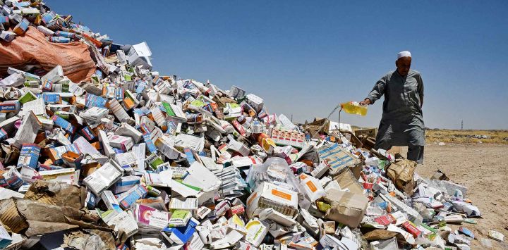 Un funcionario afgano vierte una sustancia química para prender fuego a un montón de medicamentos caducados confiscados en un campo a las afueras de Mazar-i-Sharif. Foto de Atif ARYAN / AFP