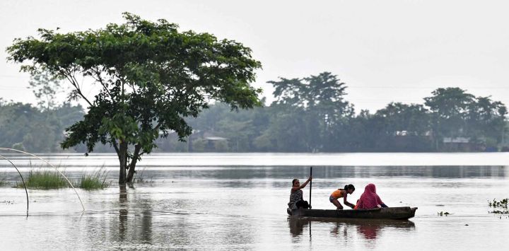 Aldeanos navegan en bote por una zona inundada tras las fuertes lluvias en Kampur, distrito de Nagaon, estado de Assam. Foto de Biju BORO / AFP