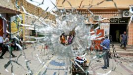 Personal de prensa se ve a través de una ventana de cristal dañada y acribillada a balazos en un centro penitenciario del distrito de Malir, Karachi. Foto de Asif HASSAN / AFP