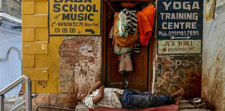 Un hombre duerme fuera de una casa en un callejón de Varanasi. Foto de Niharika KULKARNI / AFP