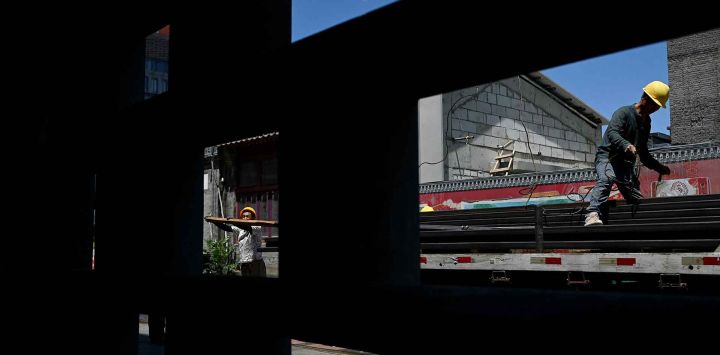 Dos trabajadores descargan materiales de un camión en una obra en construcción en Pekín. Foto de Wang Zhao / AFP 