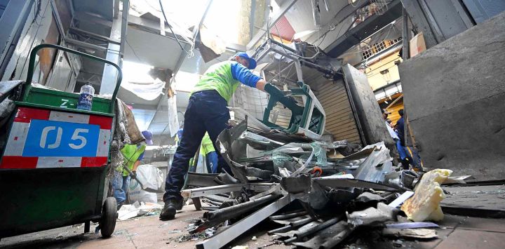 Empleados municipales retiran escombros de un pequeño local comercial afectado por un artefacto explosivo en el sector Bahía del centro de Guayaquil, Ecuador. Foto de Rodrigo BUENDIA / AFP
