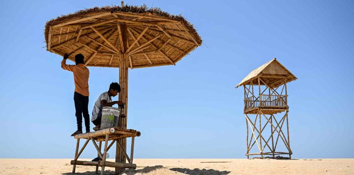 Trabajadores instalan un refugio temporal para dar sombra en la playa Marina en un caluroso día de verano en Chennai. Foto de R. Satish BABU / AFP