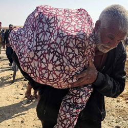 Un anciano camina con un saco al hombro mientras palestinos desplazados reciben ayuda humanitaria. Foto de AFP | Foto:AFP
