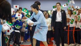 La princesa japonesa Kako de Akishino recoge y devuelve una bandera brasileña a un niño durante una visita a la Sociedad Brasileña. Foto de Miguel SCHINCARIOL / AFP
