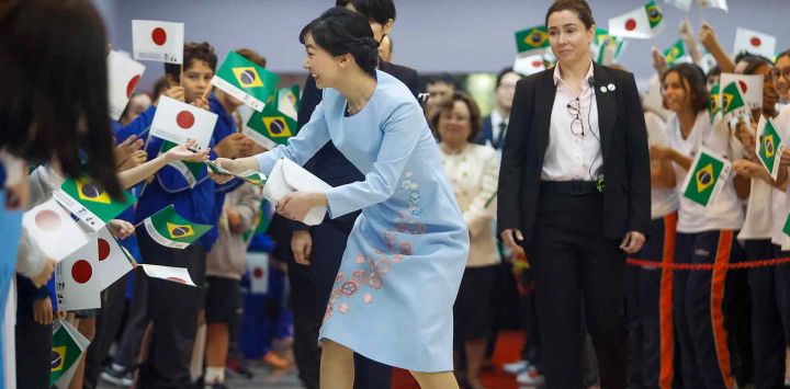 La princesa japonesa Kako de Akishino recoge y devuelve una bandera brasileña a un niño durante una visita a la Sociedad Brasileña. Foto de Miguel SCHINCARIOL / AFP