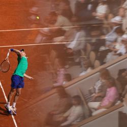El italiano Jannik Sinner le sirve al español Carlos Alcaraz mientras los espectadores se reflejan en un cristal en la tribuna, durante su partido final individual masculino de tenis Abierto de Francia en la cancha Philippe-Chatrier en el Complejo Roland-Garros en París. | Foto:DIMITAR DILKOFF / AFP